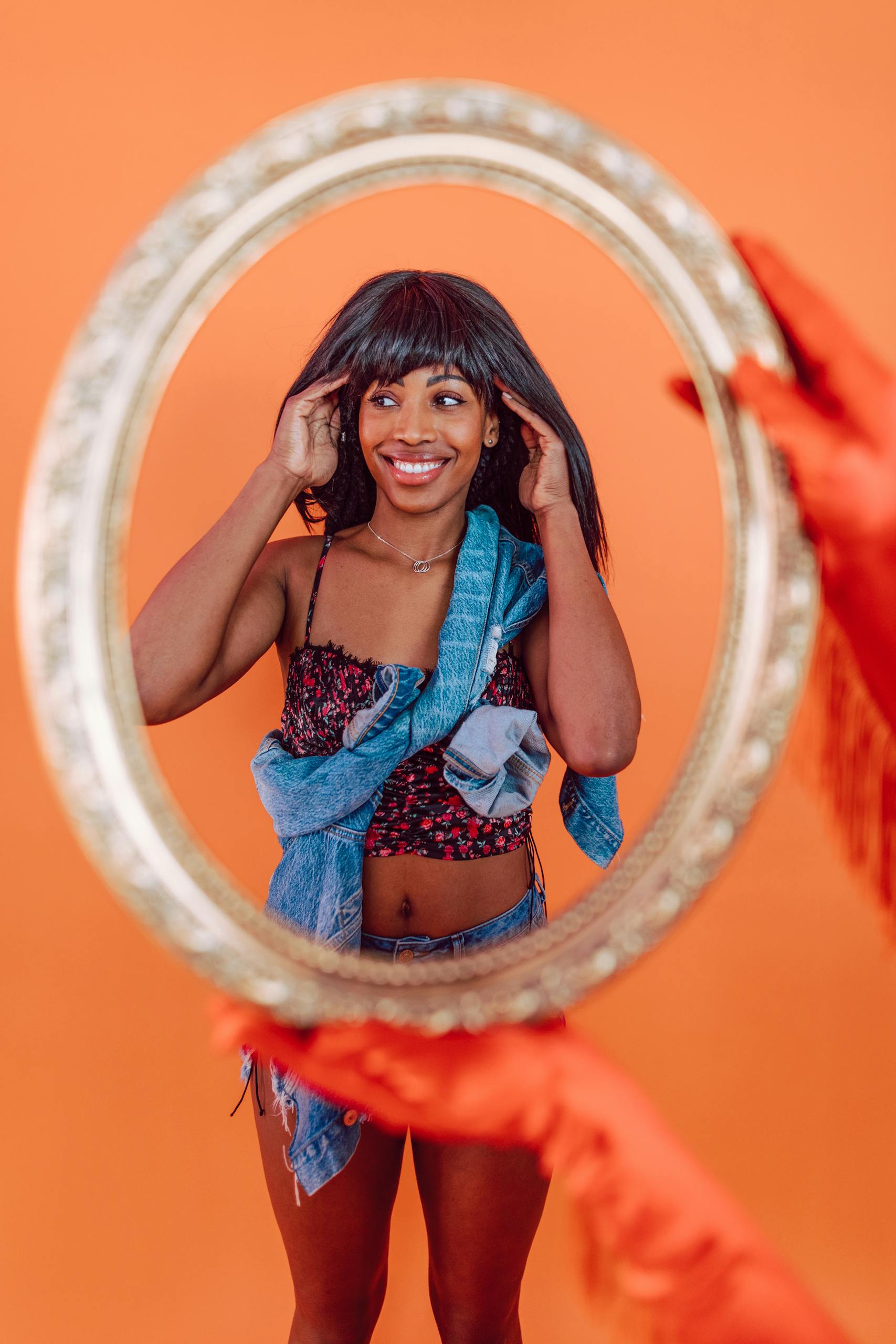 Smiling woman with fashion-forward hair looks into ornate mirror
